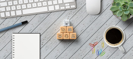 cubes with e-learning symbols on wooden table with office equipment