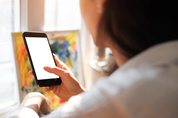 Cropped shot view of woman hands holding smart phone with blank copy space screen for your text message or information content, female reading text message on cell telephone during in urban setting.