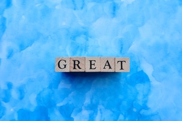 'GREAT' word made with wooden blocks on blue paper