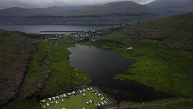 Abandoned football pitch Eidi campsite on Faroe Islands coast, aerial reveal view