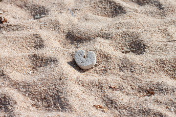 Old heart shaped foam that was left on the sand In the heat of the sun.