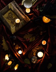 Candles, autumn leaves and a mystical book. Fairytale witch desktop. Mysterious magic background.