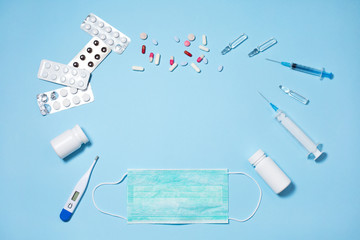 Medical pills and capsules in packs, an injector syringe on blue background