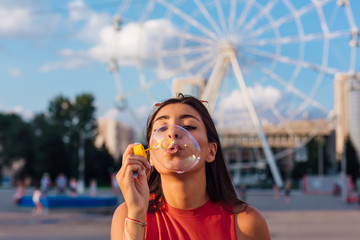 Beautiful young woman blowing soap bubbles outdoors
