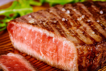 Grilled rare angus beef steak on wooden board.