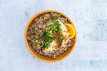 Russian, Ukrainian traditional cooked buckwheat grain porridge in bowl with parsley, herbs, onion, butter. Vegan vegetarian diet food. Homemade