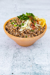 Russian, Ukrainian traditional cooked buckwheat grain porridge in bowl with parsley, herbs, onion, butter. Vegan vegetarian diet food. Homemade