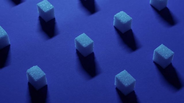 A 4K tilt up view of a unique cubic background with white sugar cubes symmetrically arranged in rows on a dark blue background, 3D effect.