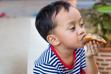 Little boy eating chocolate ice cream with bread,  Child Mouth Smeared with Chocolate.
