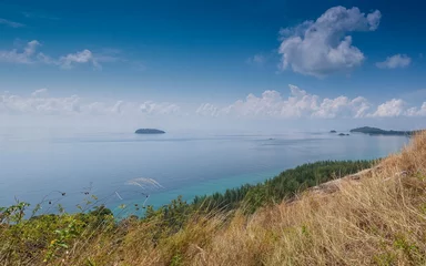 Fotobehang Mountain view of pine forest seaside with Lipe island in blue-green sea and blue sky background, taken from Chado Cliff view point, Adang island, Tarutao Marine National Park, Satun, southern Thailand © Yuttana Joe