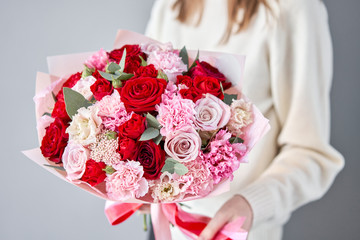 European floral shop. Red and pink Beautiful bouquet of mixed flowers in womans hands. the work of the florist at a flower shop. Delivery fresh cut flower.