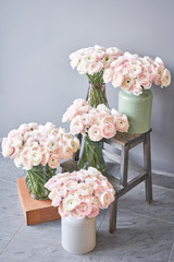 Spring background, flower Wallpaper. Persian buttercup. Bunch pale pink ranunculus flowers on light gray background. Glass vase on vintage wooden table. Wallpaper