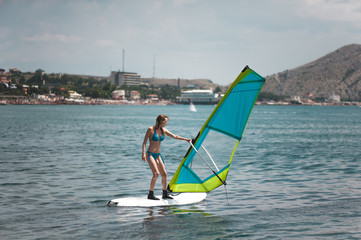 Young slim woman with sports figure learns to windsurf