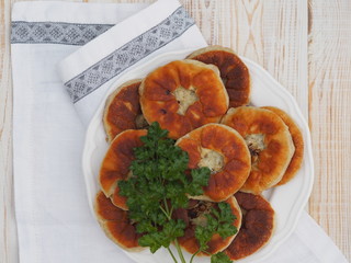 Belyasha homemade baking with meat on a white rustic wooden table.