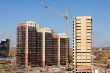 Construction of high-rise residential building. cranes working on building complex, with clear blue sky