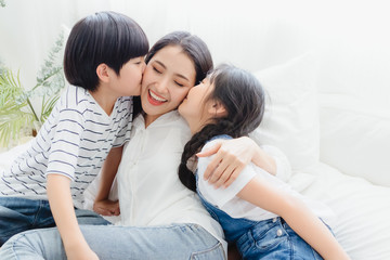 Lovely happy Asian family at cozy home. Son and daughter kiss mother with enjoy ,relax and playful together in bedroom. Happiness relationship and bonding of love between parent and children moment