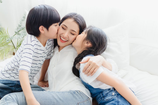 Lovely Happy Asian Family At Cozy Home. Son And Daughter Kiss Mother With Enjoy ,relax And Playful Together In Bedroom. Happiness Relationship And Bonding Of Love Between Parent And Children Moment