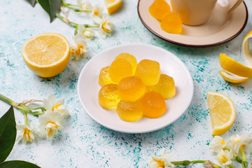 Lemon jelly candies with fresh lemons on light background,top view