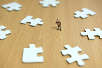 Business strategy conceptual photo - miniature businessman pointing on  jigsaw puzzle 