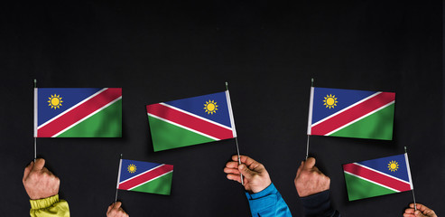 Hands holds flags of Namibia on dark background