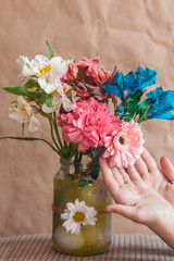 Woman touching colorful spring flowers in glass jar