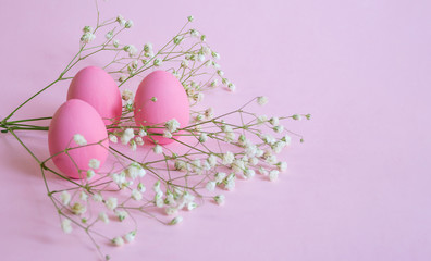Easter eggs tinted in pink and gypsophila flowers on an isolated pink background. Happy Easter and...