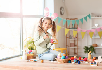 Little girl painting Easter eggs at home