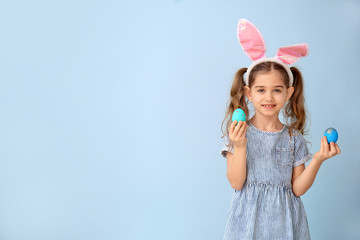 Obraz na płótnie Canvas Little girl with Easter eggs and bunny ears on color background