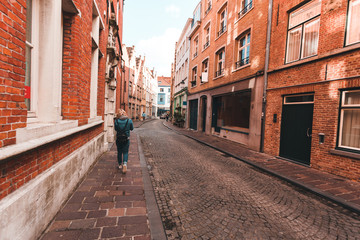 Fototapeta na wymiar A woman walks along an empty street in Bruges, Belgium.
