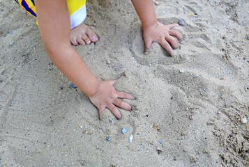 Close up hands of baby playing in garden with soil.