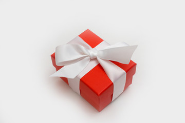 Red box with a bandaged white ribbon on an isolated background. A gift for a woman.