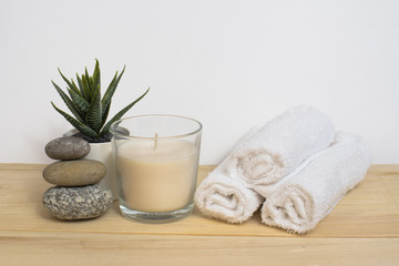 Obraz na płótnie Canvas Spa, relaxation and relaxation. Candle, towel, stones and a flower on a wooden and white background.