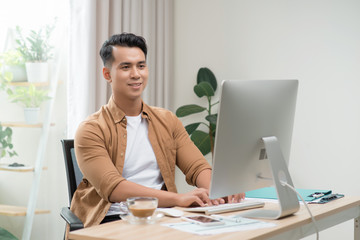 Happy Asian freelancer man is working on his computer