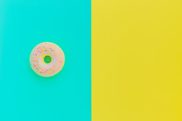 Flat lay antistress toy squish in form of pink donut with sprinkles. Bright yellow blue background. Compressing, soft, squeezable items to relieve stress, problems, anxieties, worries. Summer concept