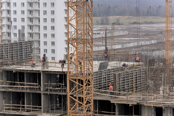 A lot of builders in helmets and masks on the top floor of a house under construction
