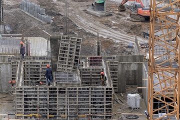 A lot of builders in helmets and masks on the top floor of a house under construction