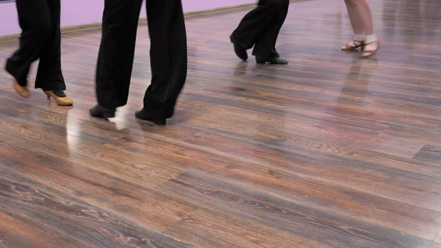A couple dancing classic dance on the parquet floor. Legs of a young man and woman in a dance against a background of parquet floor. Close up 