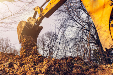 The excavator performs excavation work by digging the ground with a bucket in the forest.