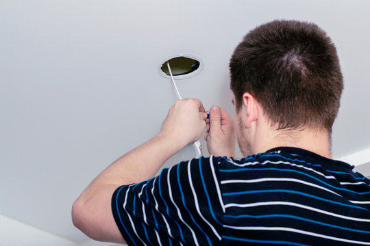 Installing spots. Electrician  installing or replacing spot light lamp into ceiling. Installing a spot in a stretch ceiling.