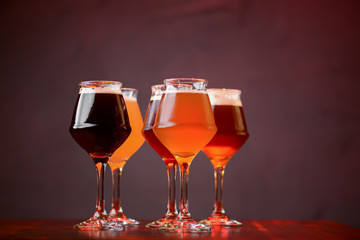 Three glasses with different beer on wooden table in a bar. Food photography concept, with copy space