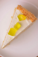 Lemon multi layered cake decorated with citron jelly and mint served on white plate on wooden background.