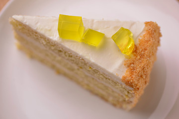 Lemon multi layered cake decorated with citron jelly and mint served on white plate on wooden...
