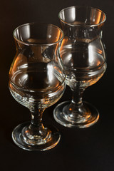 Two empty beer glasses over black background.