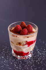 Italian dessert panna cotta with raspberries and cocoa powder served in small glass over black...