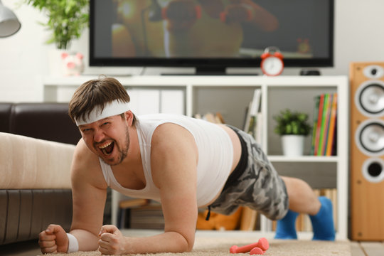 Young Attractive Fitness Man Lies On A Fat Mat With Overweight Performs Stretching Exercises And Smiles