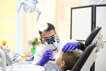 dentist is diagnosing the child while assistant in dental clinic