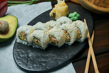 Classic japanese sushi rolls with soft crab avocado. California roll on a black plate with chopsticks. Japanese cuisine. Healthy seafood