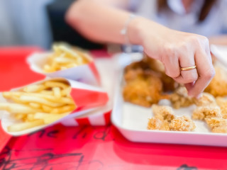 Woman eating fried chicken in the shop food and drink backgrounds