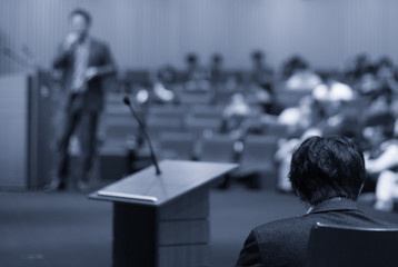 Asian Speaker or lecture with casual suit on the stage presenting via projector screen in the conference hall or seminar meeting room to audience, Business Education and Seminar concept