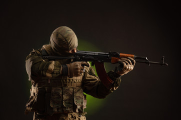 soldier militia saboteur in military clothing with a Kalashnikov rifle on a dark background